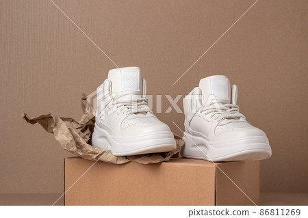 Eco leather shoes. A pair of beige sneakers on brown background. Minimal style. Casual sport lifestyle concept 86811269