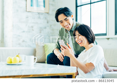 看一台智能手機的年輕夫婦在客廳 看一台智能手機的年輕夫婦在客廳 86813045