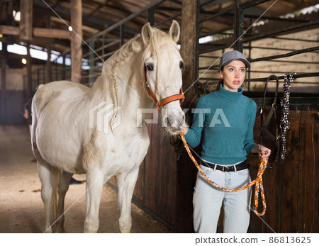 Portrait of woman with white horse in stable Portrait of woman with white horse in stable 86813625
