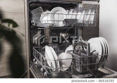 Front view of open automatic stainless steel built-in fully integrated top control dishwasher range machine with clean utensils, cutlery, glasses, dishes, plates inside in modern home kitchen Front view of open automatic stainless steel built-in fully integrated top control dishwasher range machine with clean utensils, cutlery, glasses, dishes, plates inside in modern home kitchen 86816595