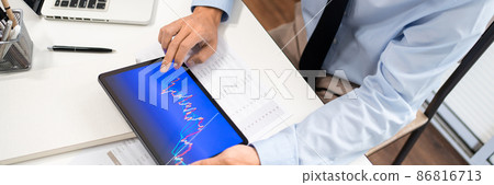 Working Man Conept The male employee sitting at his desk, holding a tablet, and touching the screen of his work Working Man Conept The male employee sitting at his desk, holding a tablet, and touching the screen of his work 86816713