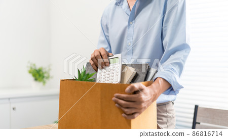 Resignation Concept The man in light blue shirt standing at the desk and putting the calculator and other stuff into the box 86816714