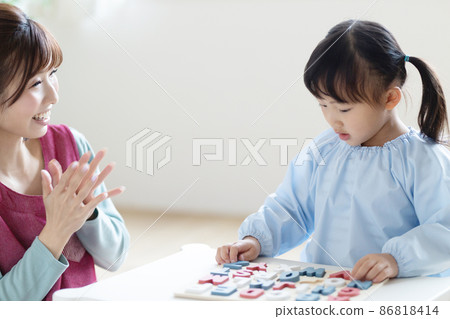 Children and nursery teachers playing with English puzzles 86818414