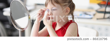 Little girl painting her eyes with baby makeup in front of mirror Little girl painting her eyes with baby makeup in front of mirror 86818796