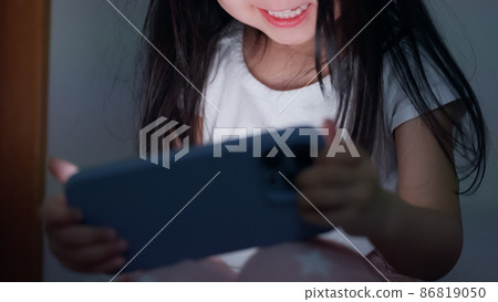 A 4-year-old child looking at a smartphone in a dark room at night A 4-year-old child looking at a smartphone in a dark room at night 86819050