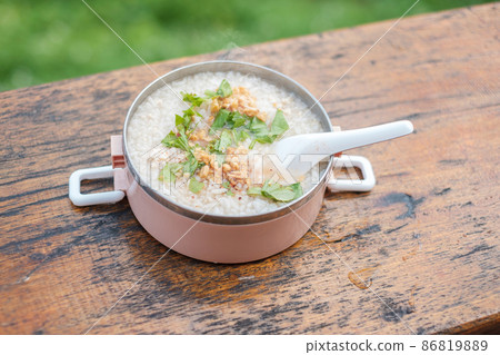 Pork porridge or rice soup with pork and vegetables on wood table against Mountain View background 86819889