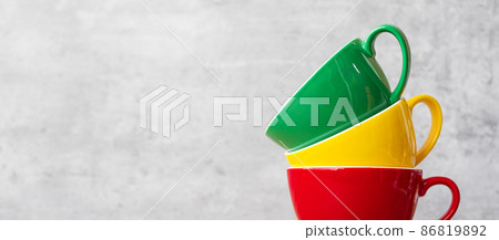 stack of colorful coffee cups on wall background at cafe. Green, yellow and red color ceramic mug on table at home. International coffee day concept 86819892