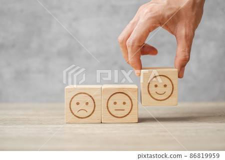 Man hand holding emotion face block. Customer choose Emoticon for user reviews. Service rating, ranking, customer review, satisfaction, mood, evaluation and feedback concept Man hand holding emotion face block. Customer choose Emoticon for user reviews. Service rating, ranking, customer review, satisfaction, mood, evaluation and feedback concept 86819959
