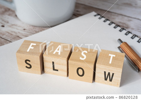 Blocks, pens, notebooks, coffee cups with "FAST" and "SLOW" written on them 86820128
