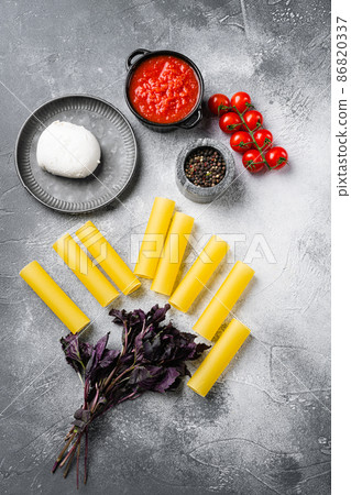 Cannelloni preparations. Minimal concept, on gray stone table background, top view flat lay Cannelloni preparations. Minimal concept, on gray stone table background, top view flat lay 86820337