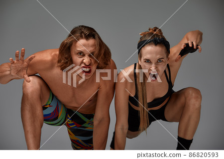 Beautiful young acrobats or gymnasts on gray background. Professional ballet couple dancing, Emotional duet performing choreographic art. Animal instinct Beautiful young acrobats or gymnasts on gray background. Professional ballet couple dancing, Emotional duet performing choreographic art. Animal instinct 86820593