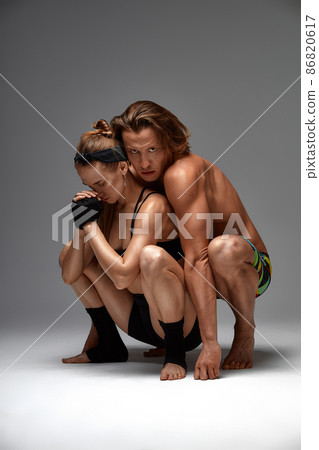 Beautiful young acrobats or gymnasts on gray background. Professional ballet couple dancing, Emotional duet performing choreographic art. Animal instinct Beautiful young acrobats or gymnasts on gray background. Professional ballet couple dancing, Emotional duet performing choreographic art. Animal instinct 86820617