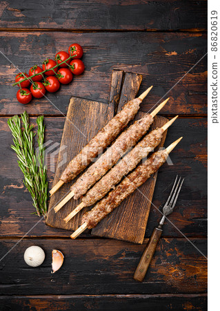Lula kebab on skewers, on serving board, on old dark wooden table background, top view flat lay 86820619