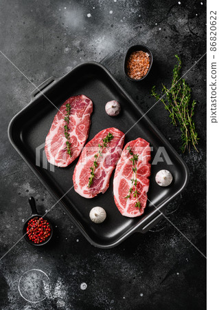 Raw pork steaks with herbs, on black dark stone table background, top view flat lay Raw pork steaks with herbs, on black dark stone table background, top view flat lay 86820622
