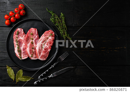 Piece of fresh raw pork from the neck, with ingredients, on black wooden table background, top view flat lay, with copy space for text 86820871