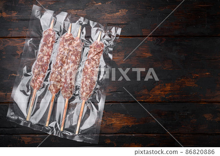 Turkish uncooked shish minced meat kofta in vacuum pack, on old dark wooden table background, top view flat lay, with copy space for text Turkish uncooked shish minced meat kofta in vacuum pack, on old dark wooden table background, top view flat lay, with copy space for text 86820886