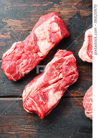 Variety of organic raw beef steakes chuck roll cut on old rustic dark wooden background, top view with space for text Variety of organic raw beef steakes chuck roll cut on old rustic dark wooden background, top view with space for text 86820970