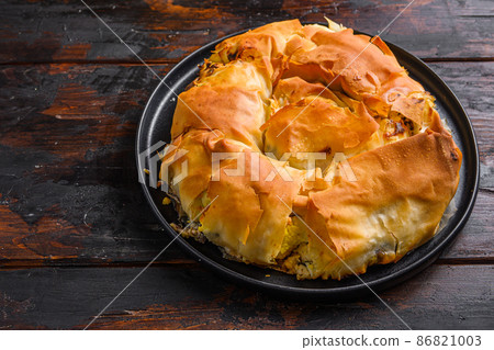 Homemade Greek spanakopita in on black plate filo spinach eggs feta side view on dark wooden background. Homemade Greek spanakopita in on black plate filo spinach eggs feta side view on dark wooden background. 86821003