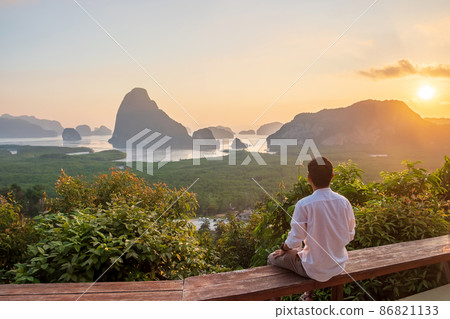 Happy traveler man enjoy Phang Nga bay view point, alone Tourist sitting and relaxing at Samet Nang She, near Phuket in Southern Thailand. Southeast Asia travel, trip and summer vacation concept 86821133