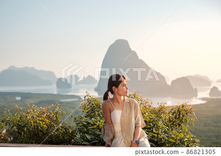 Happy traveler woman enjoy Phang Nga bay view point, alone Tourist sitting and relaxing at Samet Nang She, near Phuket in Southern Thailand. Southeast Asia travel, trip and summer vacation concept 86821305