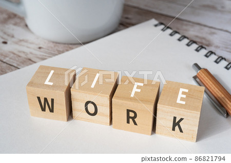 Image of work-life balance | "WORK" and "LIFE" building blocks, pens, notebooks, coffee cups Image of work-life balance | "WORK" and "LIFE" building blocks, pens, notebooks, coffee cups 86821794