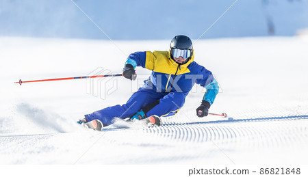 A young aggressive skier on an alpine slope demonstrates an extreme carving skiing style. A young aggressive skier on an alpine slope demonstrates an extreme carving skiing style. 86821848