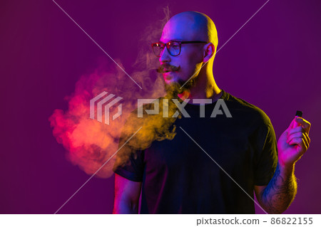 Adult man person vaping, blowing smoke in studio. color filters. Vaping concept  86822155