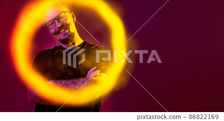 young bald man looking at the camera through a ring of smoke. color filters. Vaping concept  86822169