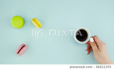 Top view of multicolored French Macarons cookies and a cup of coffee on a pastel blue background 86822205