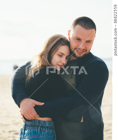 Young adult couple standing on coast and huging each other. Handsome smiling man embracing woman 86822559