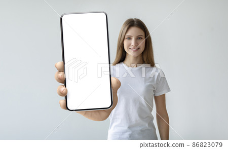 Lady holding mobile phone with empty screen in her hand Lady holding mobile phone with empty screen in her hand 86823079
