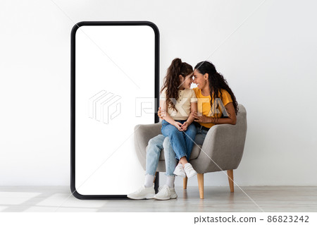 Arab family sitting near big smartphone with blank screen, advertising your application or website, mockup 86823242