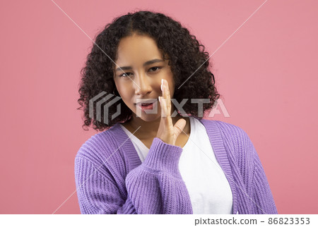 Young black woman whispering secret, sharing confidential information, spreading gossip on pink studio background Young black woman whispering secret, sharing confidential information, spreading gossip on pink studio background 86823353