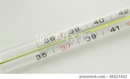 A close-up of a glass mercury thermometer shows a low temperature 86823402