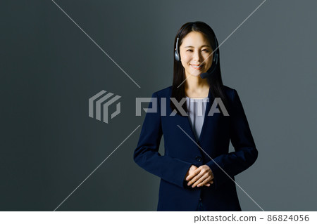 A smiling young female operator in a suit and wearing a headset 86824056