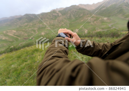 Hiker on high altitude mountain top checking the sports watch 86824941