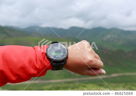 Hiker on high altitude mountain top checking the altimeter on the sports watch 86825089