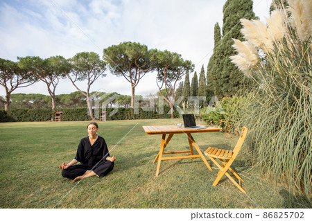 Girl meditating and practicing yoga on green lawn Girl meditating and practicing yoga on green lawn 86825702