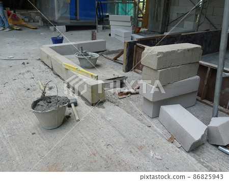 SEREMBAN, MALAYSIA -FEBRUARY 2, 2021: Blockwork by construction workers at the construction site. The bricks are stacked to form the walls as designed by the architect. SEREMBAN, MALAYSIA -FEBRUARY 2, 2021: Blockwork by construction workers at the construction site. The bricks are stacked to form the walls as designed by the architect. 86825943