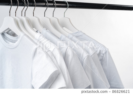 Clothes hang on clothing rack over white background. 86826621