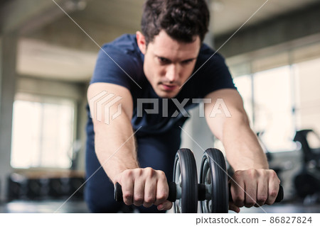 Sportsman or Handsome doing exercise with abs roller wheel to strengthen his abdominal muscle in gym 86827824