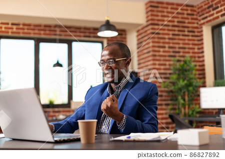 Company employee clenching fist to celebrate business achievement at job Company employee clenching fist to celebrate business achievement at job 86827892
