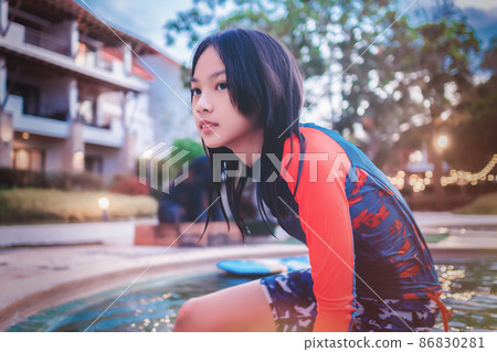 Asian girl kid in orange swimwear is playing in vacation resort swimming pool. Asian girl kid in orange swimwear is playing in vacation resort swimming pool. 86830281