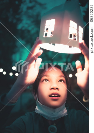 A child is looking at festive decoration light house lamp in winter festival new year celebration. A child is looking at festive decoration light house lamp in winter festival new year celebration. 86830282