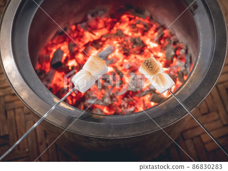 Grilled marshmallow on flame barbecue roasted in campfire for winter part outdoor camping activity at night. Grilled marshmallow on flame barbecue roasted in campfire for winter part outdoor camping activity at night. 86830283