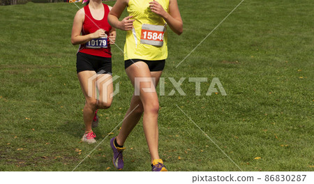 Two girls running a 5K race on grass 86830287