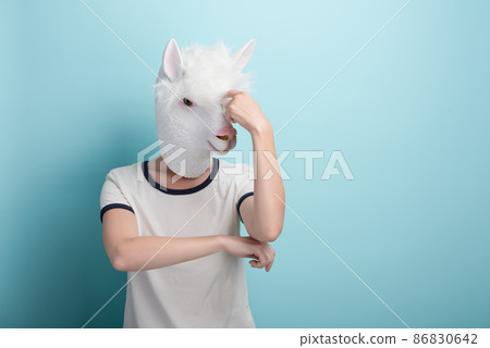 Young woman in alpaca mask scratching her head, thinking or in doubt, isolated on blue background  86830642