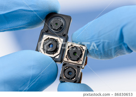 Smartphone camera modules in scientist hands. Different modern sensor sizes and technology used. Smartphone camera modules in scientist hands. Different modern sensor sizes and technology used. 86830653