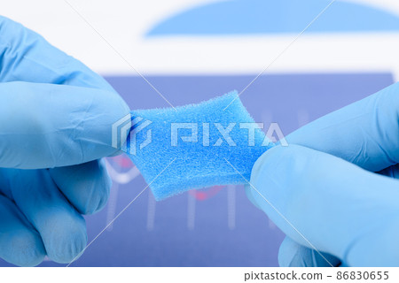 Blue porous foam material stretched in scientist hands in laboratory. Blue porous foam material stretched in scientist hands in laboratory. 86830655