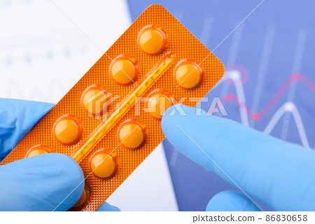 Scientist point to a single pill in blister pack Scientist point to a single pill in blister pack 86830658